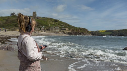 A child wearing headphones stares out to see while listening to audio.